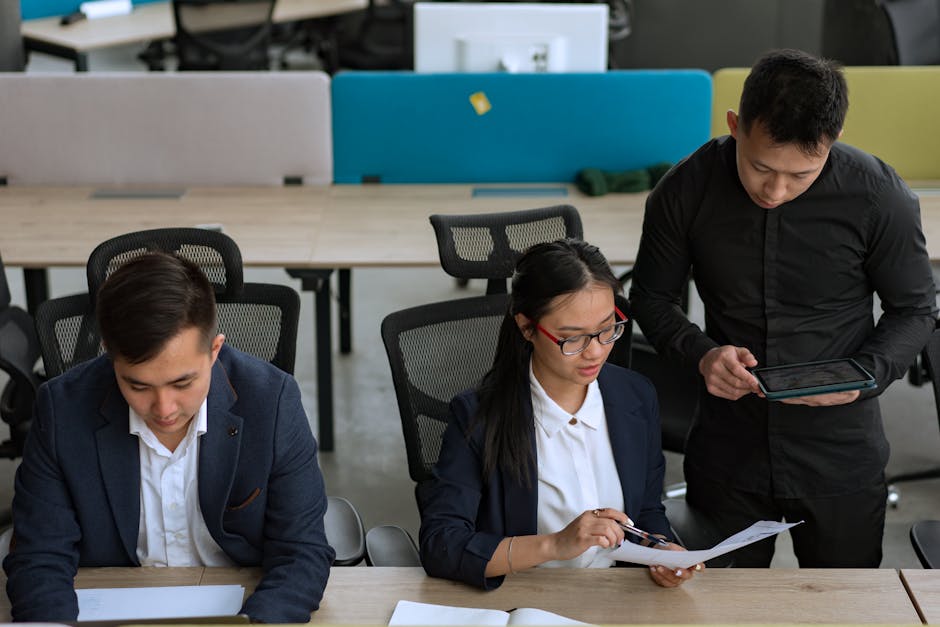 A professional team collaborating in a modern office setting, focusing on documents and technology.